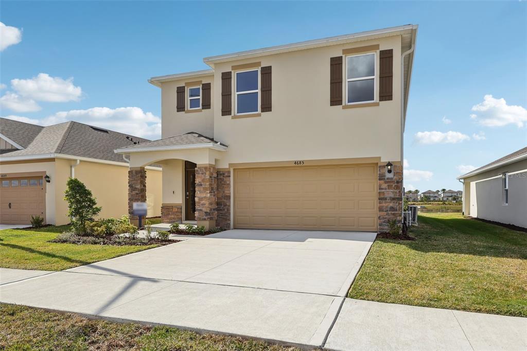 A two-story suburban house features a tan stucco exterior, stone accents, and a two-car garage — 1189 CUMBERLAND TRAIL DRIVE, LAKE HAMILTON, FL