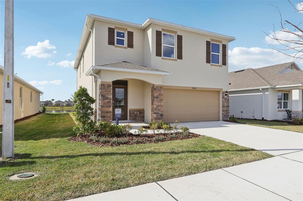 A two-story suburban house with a tan stucco exterior, stone accents, and a two-car garage — 1189 CUMBERLAND TRAIL DRIVE, LAKE HAMILTON, FL