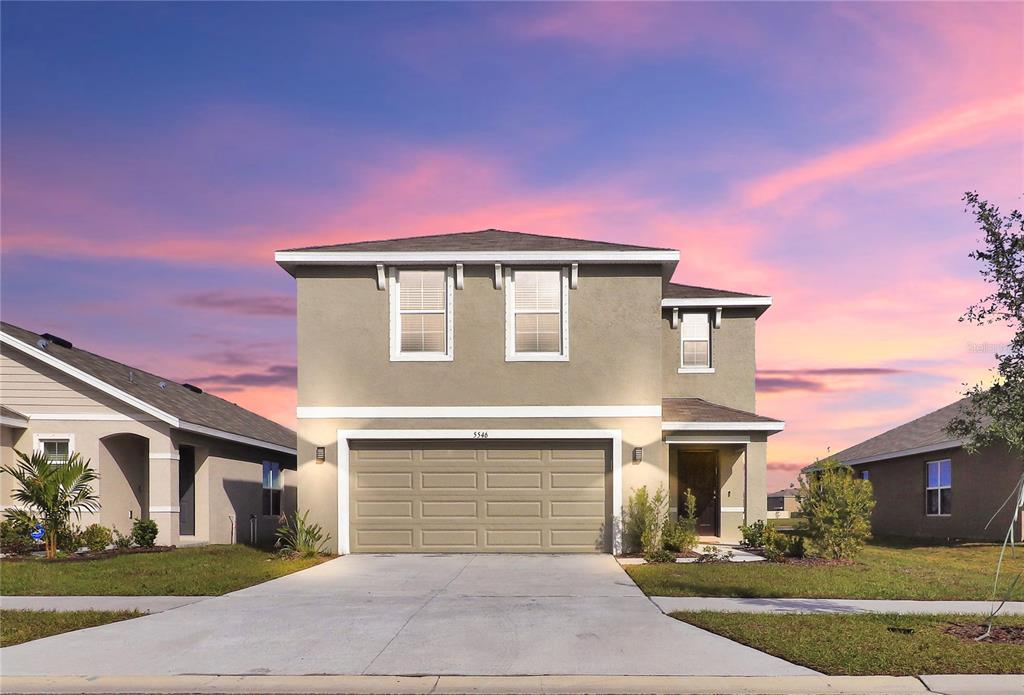 A two-story suburban house with a tan stucco exterior and a two-car garage — 5546 LOGAN CAVE AVENUE, WIMAUMA, FL