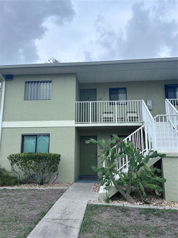 A two-story apartment building with a green stucco exterior, a balcony, and an outdoor staircase — 25225 RAMPART BOULEVARD UNIT 105, PUNTA GORDA, FL