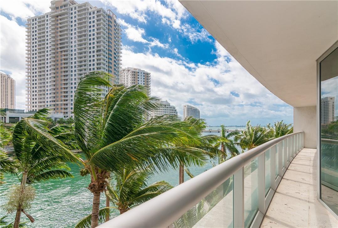A balcony with a glass railing overlooks a canal, palm trees, and high-rise buildings — 465 Brickell Avenue # 419, Miami FL 33131, MIAMI, FL