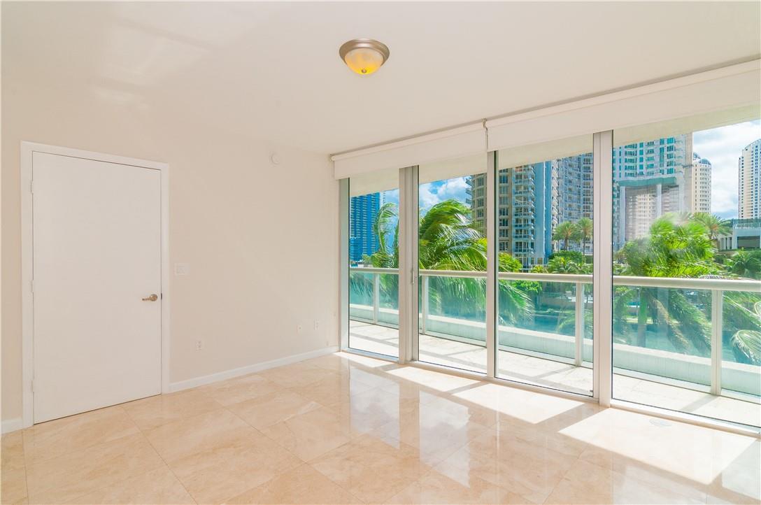 An empty room with light tile floors, a white door, and floor-to-ceiling windows overlooking buildings — 465 Brickell Avenue # 419, Miami FL 33131, MIAMI, FL