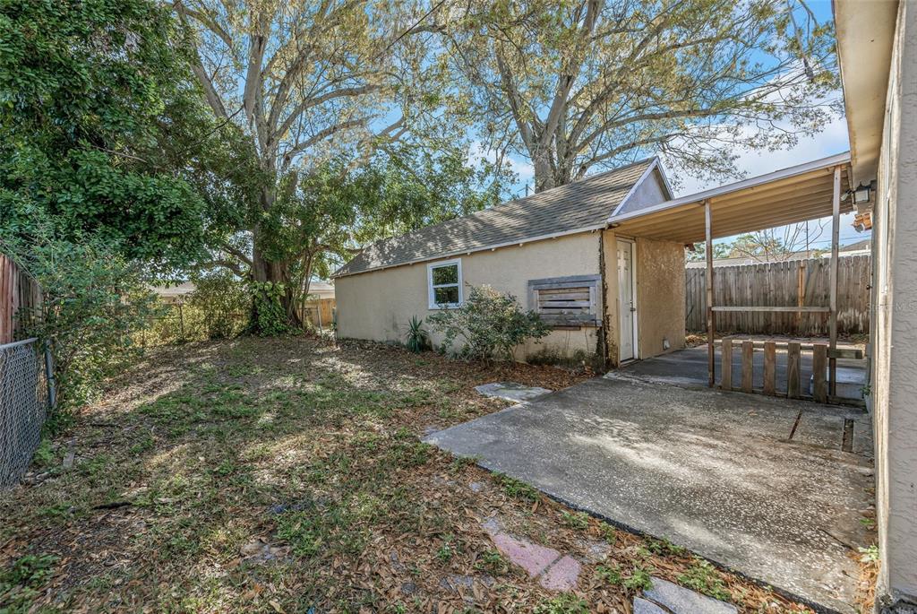 A detached garage with a carport sits in a backyard with a concrete patio area — 4139 26TH STREET N, ST PETERSBURG, FL