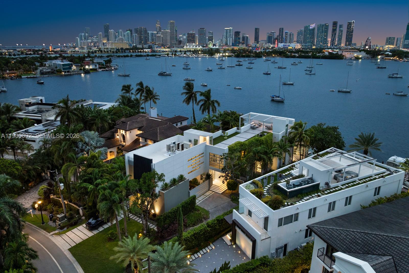 An aerial view shows a modern white waterfront mansion with rooftop terraces and lush landscaping — 440 S Hibiscus Dr, Miami Beach FL 33139, MIAMI BEACH, FL
