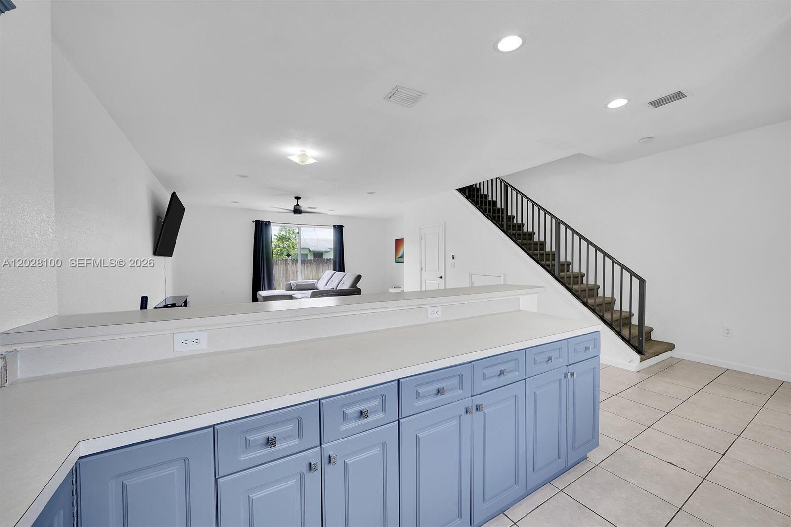 A kitchen island with blue cabinets faces a living area with a staircase — 2620 Pierce St # A3, Hollywood FL 33020, HOLLYWOOD, FL