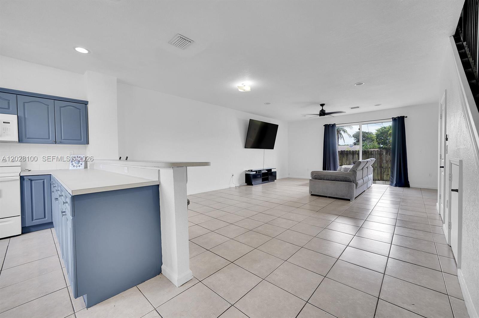 A kitchen with blue cabinets overlooks an open-concept living area with tile floors — 2620 Pierce St # A3, Hollywood FL 33020, HOLLYWOOD, FL