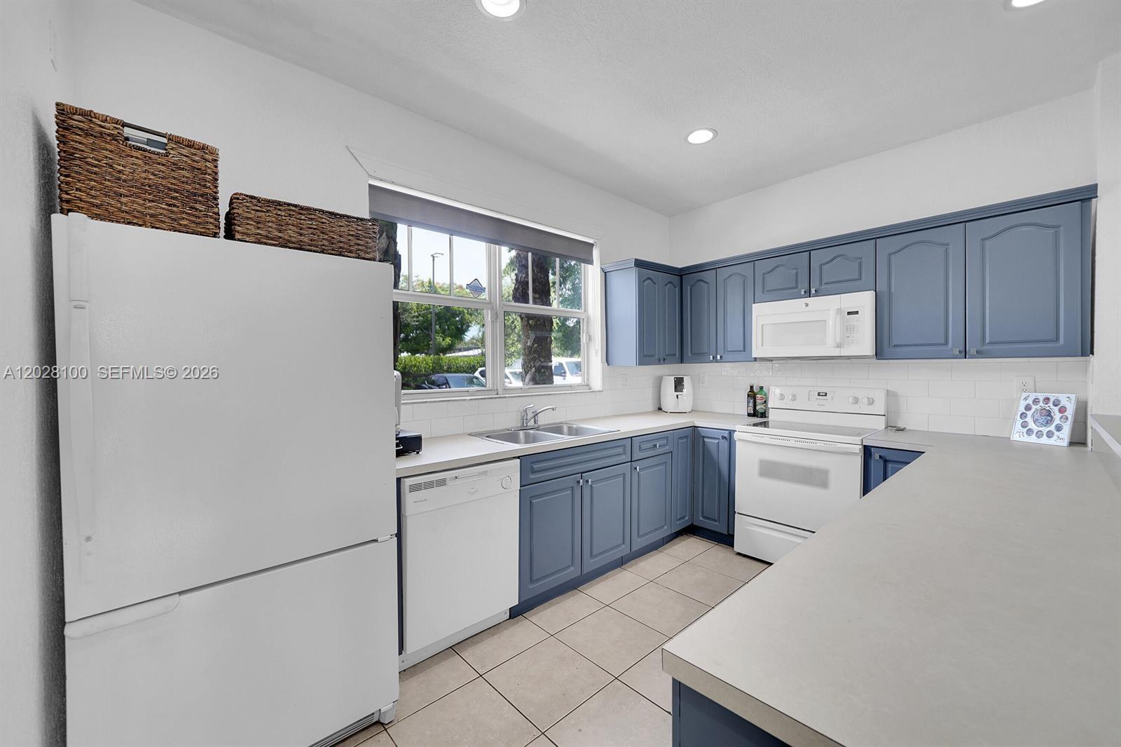 A kitchen features blue cabinets, white appliances, a double sink, and light-colored tile flooring — 2620 Pierce St # A3, Hollywood FL 33020, HOLLYWOOD, FL