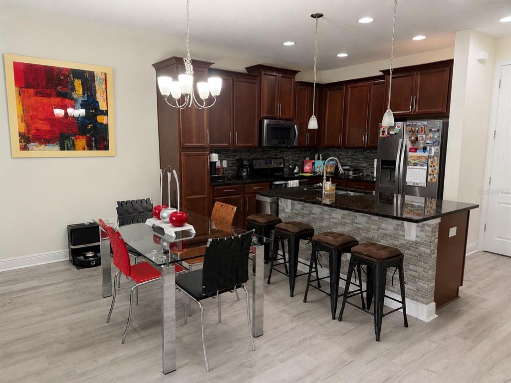 A kitchen with dark wood cabinets, granite countertops, and an adjacent dining area with chairs — 14164 SWANLEY STREET, ORLANDO, FL