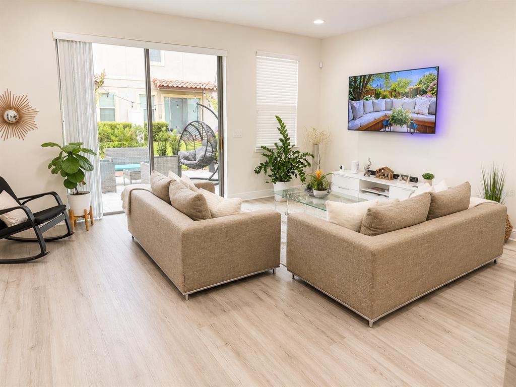 A living room features two beige sofas, a glass coffee table, and a sliding glass door — 14164 SWANLEY STREET, ORLANDO, FL