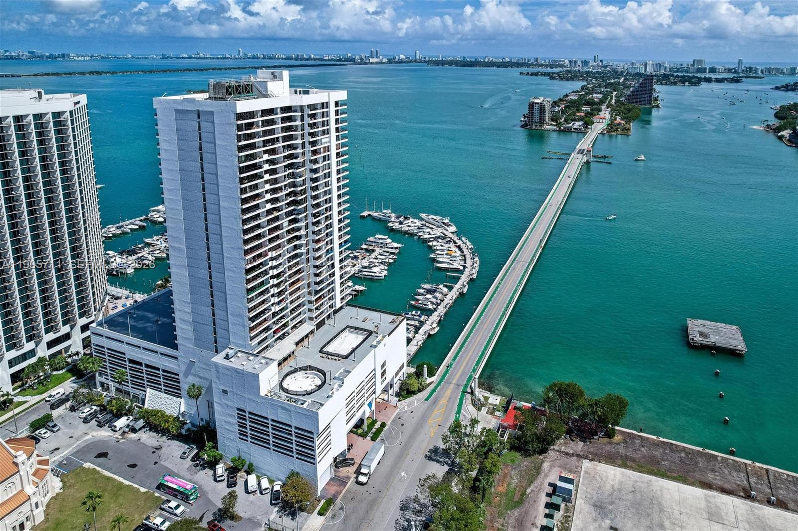 An aerial view shows a tall white residential building next to a marina and bridge — 555 NE 15th St # 15B, Miami FL 33132, MIAMI, FL