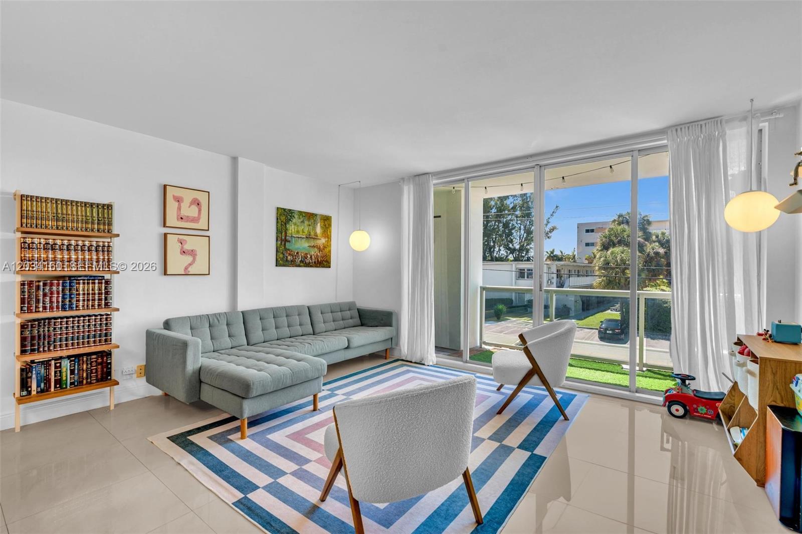 A living room features a grey sectional sofa, two armchairs, a bookshelf, and glass doors — 9381 E Bay Harbor Dr # 202s, Bay Harbor Islands FL 33154, BAY HARBOR ISLANDS, FL