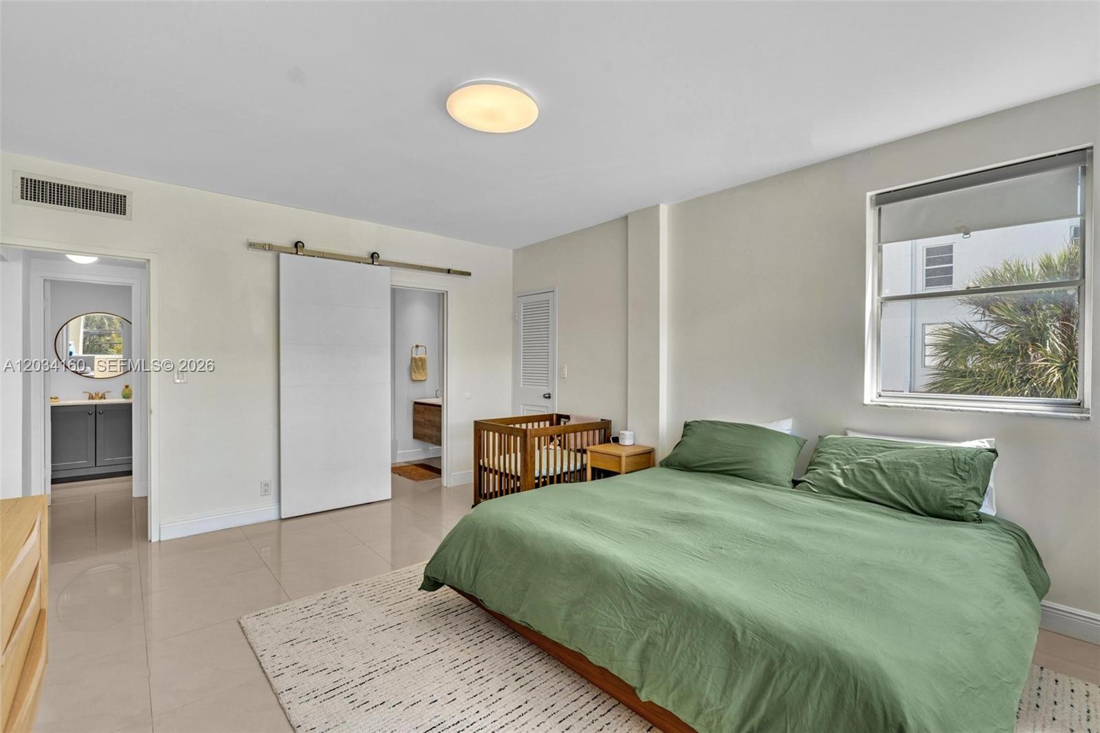 A bedroom features a green bed, a wooden crib, tile flooring, and a sliding door — 9381 E Bay Harbor Dr # 202s, Bay Harbor Islands FL 33154, BAY HARBOR ISLANDS, FL