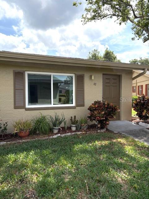 The exterior of a tan, single-story house features a front door and a large window — 302 CANTON COURT UNIT 62, SUN CITY CENTER, FL