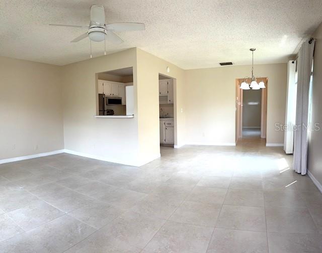 An open-concept living area features light-colored tile flooring, a ceiling fan, and a kitchen pass-through — 302 CANTON COURT UNIT 62, SUN CITY CENTER, FL