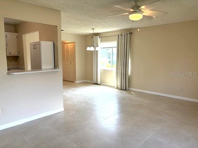 A living room features light tile flooring, a ceiling fan, and a kitchen pass-through window — 302 CANTON COURT UNIT 62, SUN CITY CENTER, FL