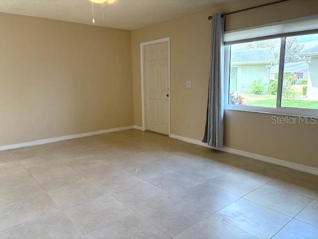 An empty room features light-colored tile flooring, a white door, and a large window — 302 CANTON COURT UNIT 62, SUN CITY CENTER, FL