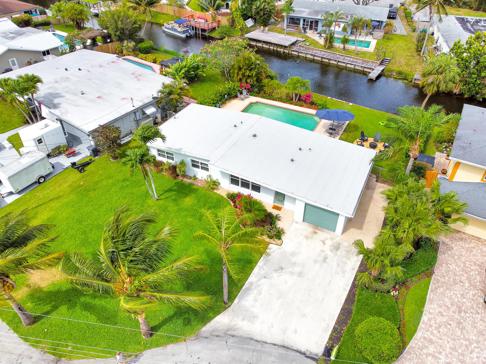 An aerial view shows a single-story house with a pool, lawn, and canal access — 6821 Kingston Drive, Lake Worth FL 33462, LAKE WORTH, FL