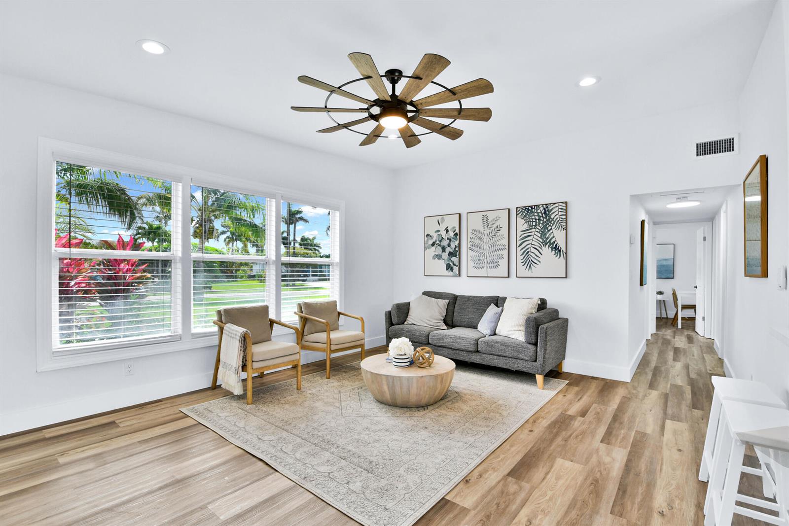 A living room features a grey sofa, two armchairs, a round coffee table, and wood flooring — 6821 Kingston Drive, Lake Worth FL 33462, LAKE WORTH, FL