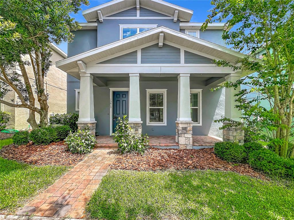 A two-story house with a covered front porch, stone-based columns, and a brick walkway — 15813 SWEET LEMON WAY, WINTER GARDEN, FL