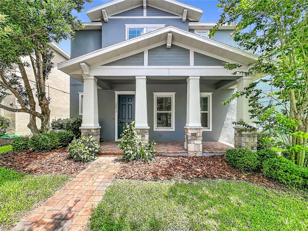 A gray house with a covered front porch, stone-based columns, and a brick walkway — 15813 SWEET LEMON WAY, WINTER GARDEN, FL