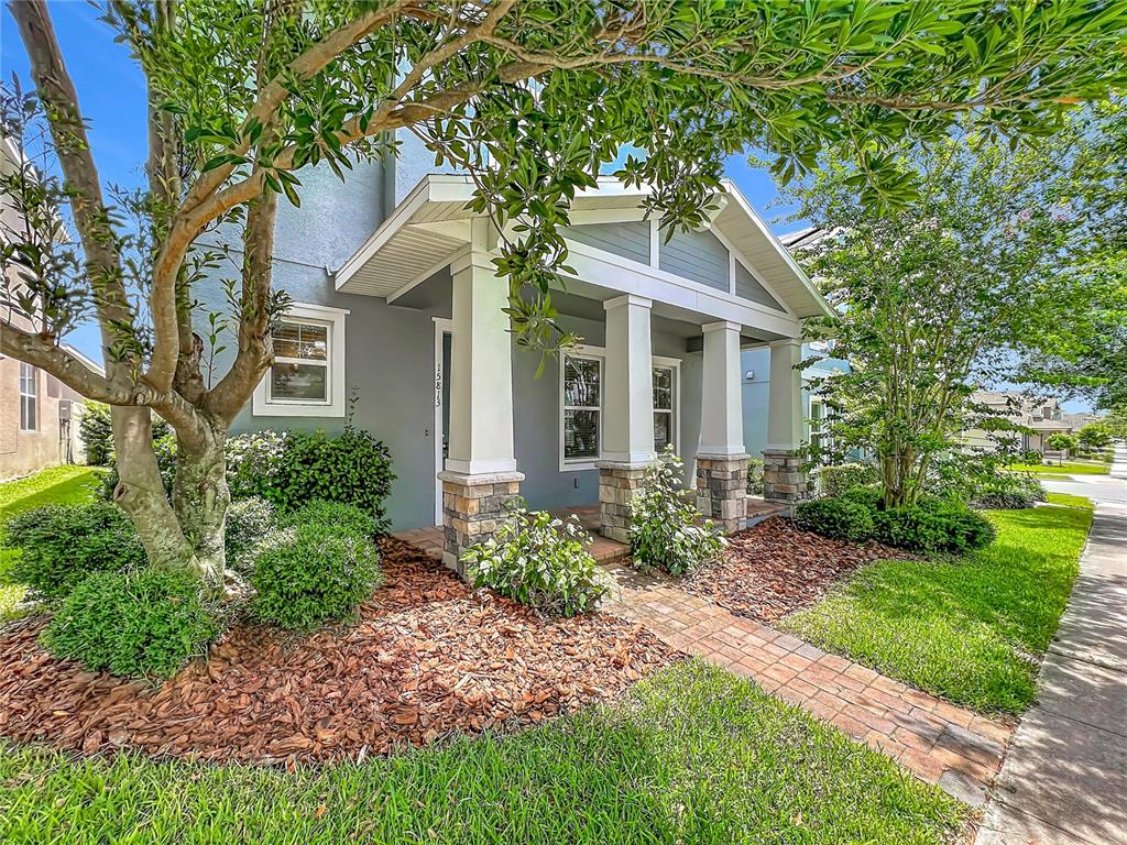 A view of a house exterior with a front porch, sidewalk, and surrounding trees — 15813 SWEET LEMON WAY, WINTER GARDEN, FL