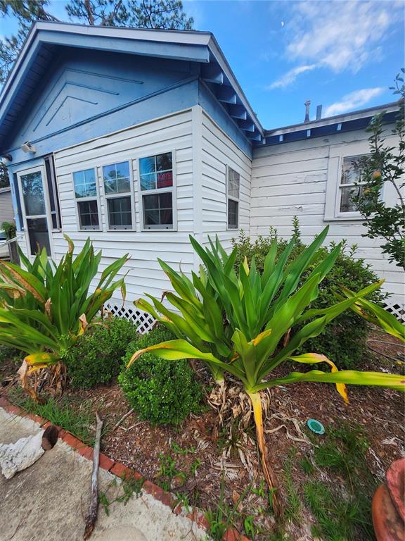 A white-sided house with blue trim features large green plants in the front yard — 1427 SE 1ST AVENUE, GAINESVILLE, FL