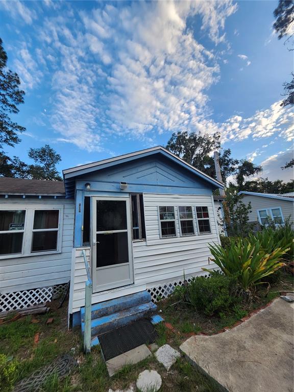 The exterior of a small, light blue and white house features a front door and steps — 1427 SE 1ST AVENUE, GAINESVILLE, FL