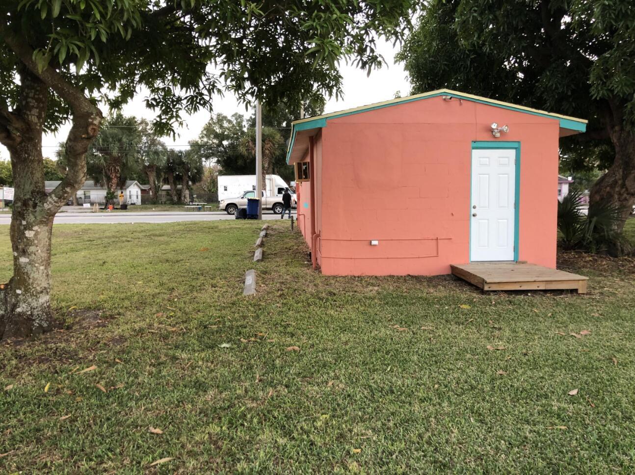 A small, peach-colored concrete block building with a white door and a wooden entry platform — 1806 Ave D, Fort Pierce FL 34950, FORT PIERCE, FL