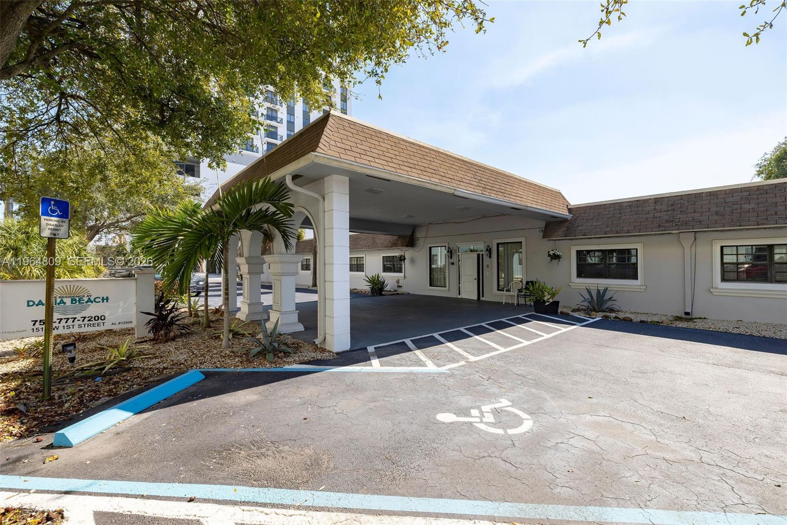 The exterior of a building features a covered entrance, a parking area, and landscaping — 151 SW 1st St, Dania Beach FL 33004, DANIA BEACH, FL