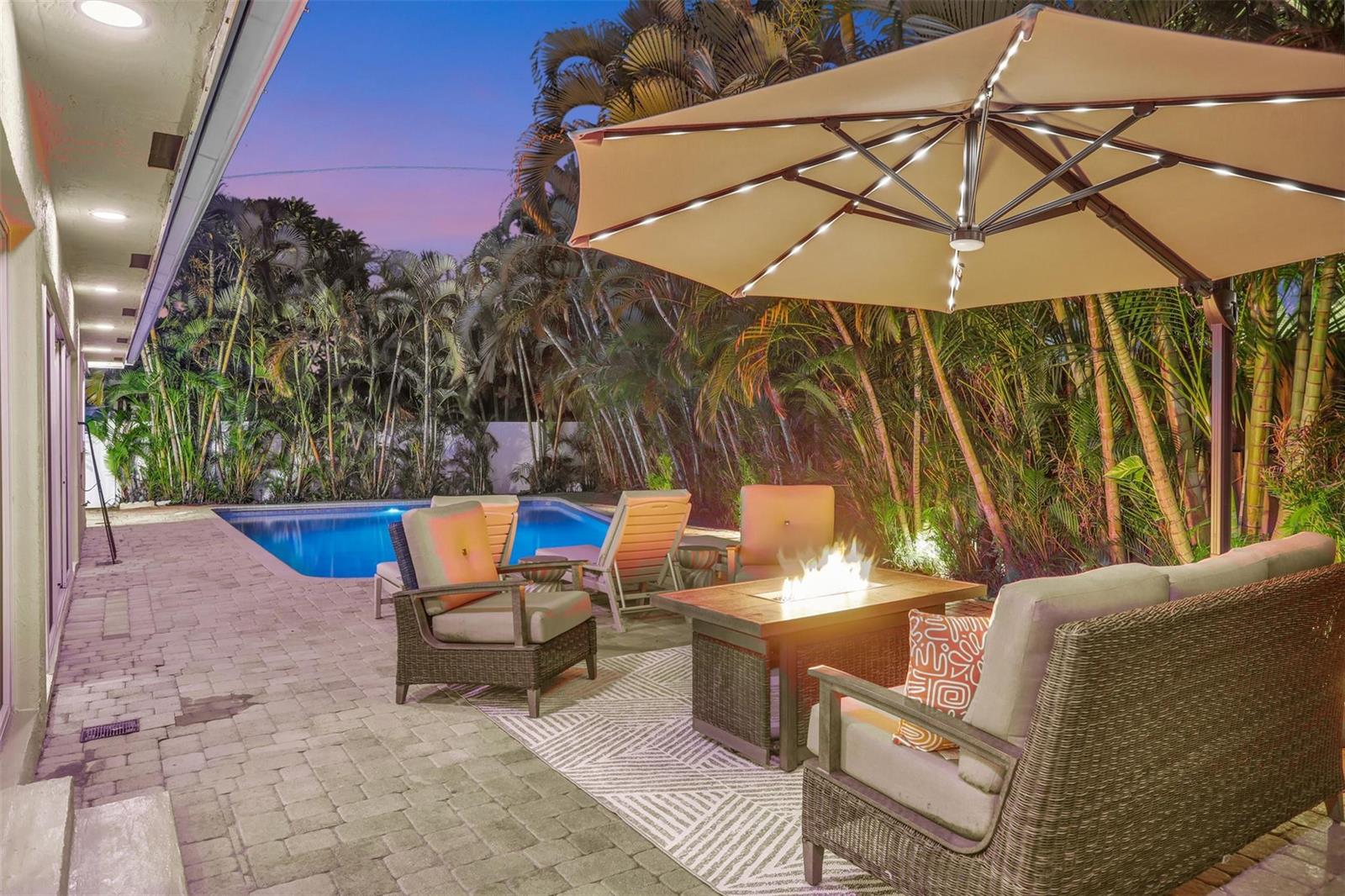 A patio with a fire pit, outdoor seating, and a pool surrounded by palm trees — 2600 N Riverside Drive, Pompano Beach FL 33062, POMPANO BEACH, FL