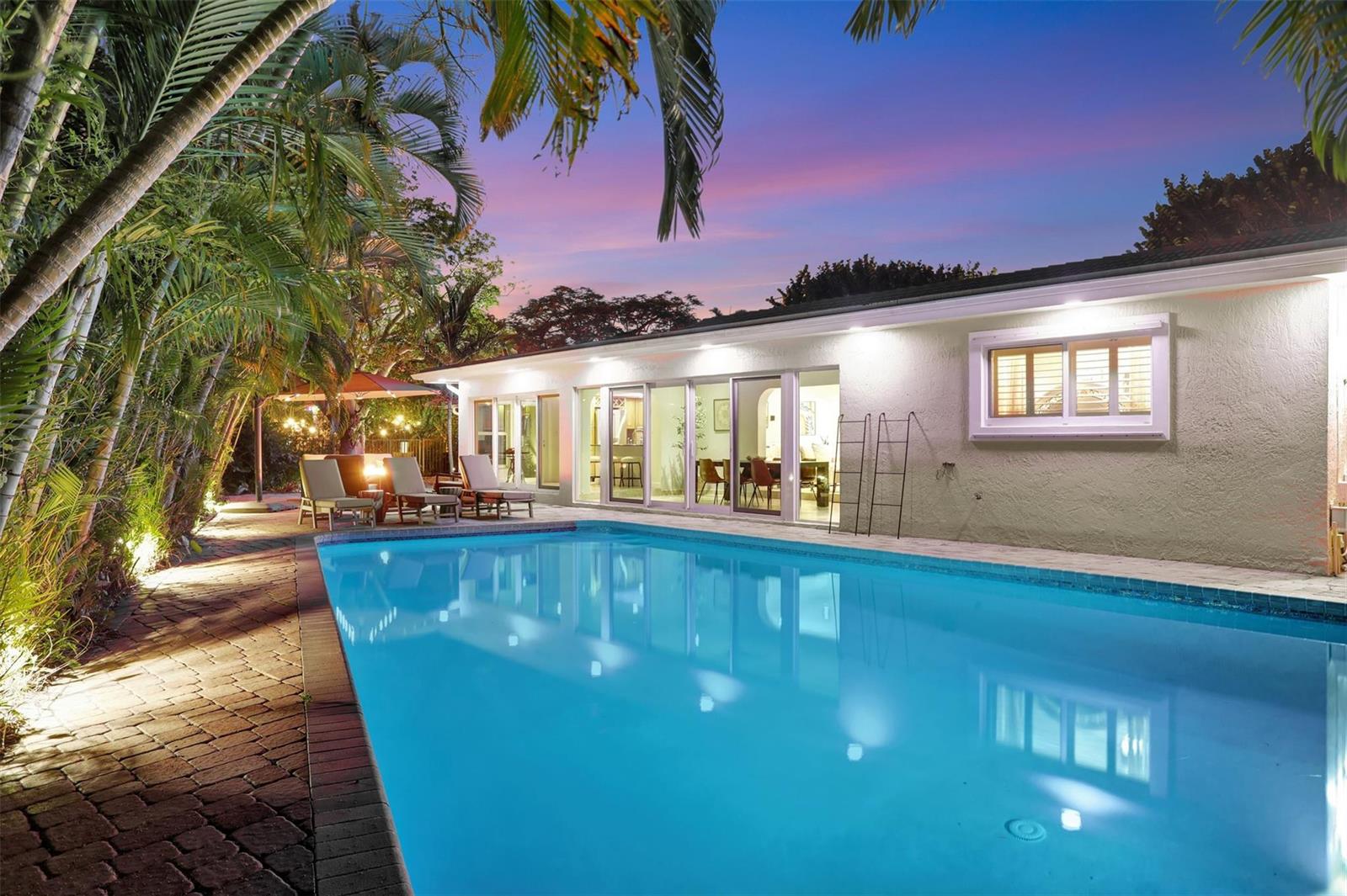 A backyard swimming pool sits in front of a single-story house with sliding glass doors — 2600 N Riverside Drive, Pompano Beach FL 33062, POMPANO BEACH, FL