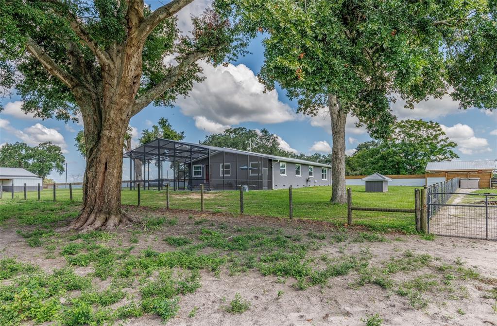 A gray house with a large screened-in porch sits on a grassy lot with trees — 1231 102ND BLVD A, WILDWOOD, FL