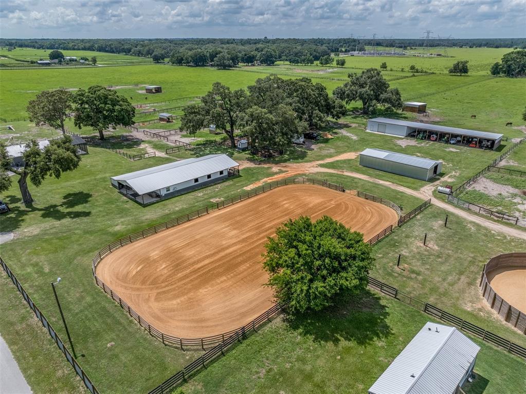An aerial view shows a horse riding arena, several outbuildings, and fenced pastures — 1231 102ND BLVD A, WILDWOOD, FL