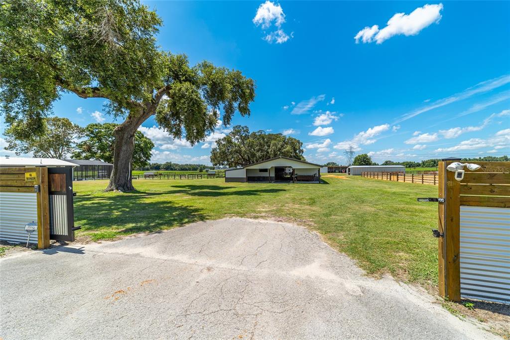 A gravel driveway leads through an open gate toward a barn on a grassy lot — 1231 102ND BLVD A, WILDWOOD, FL