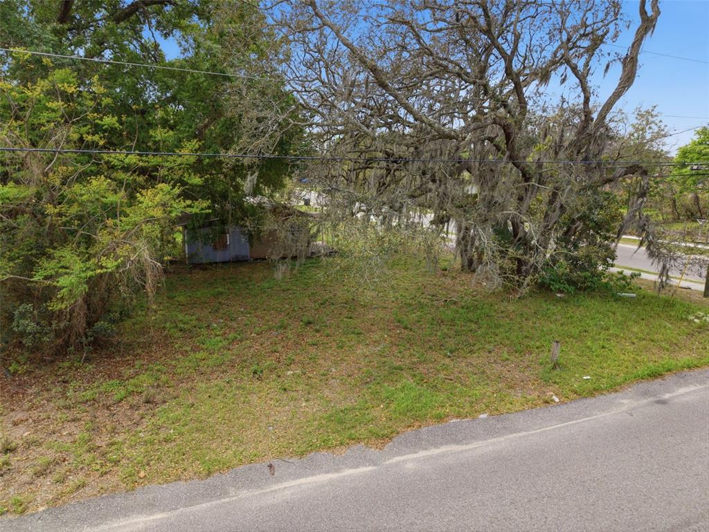 An elevated view shows a grassy, tree-covered lot with a small, weathered structure in the back — 1301 S CENTRAL AVENUE, APOPKA, FL