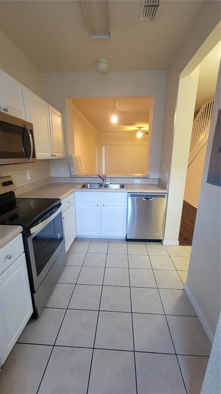 A kitchen with white cabinets, stainless steel appliances, and light-colored tile flooring — 4316 NW 48TH UNIT 106, GAINESVILLE, FL