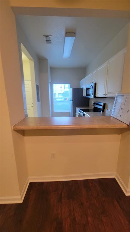 A kitchen with white cabinets and a breakfast bar overlooks a dining area — 4316 NW 48TH UNIT 106, GAINESVILLE, FL