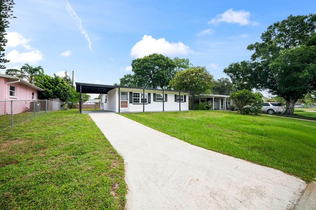A white single-story house features a carport, a concrete driveway, and a grassy front yard — 2204 SHELBY DRIVE, MELBOURNE, FL