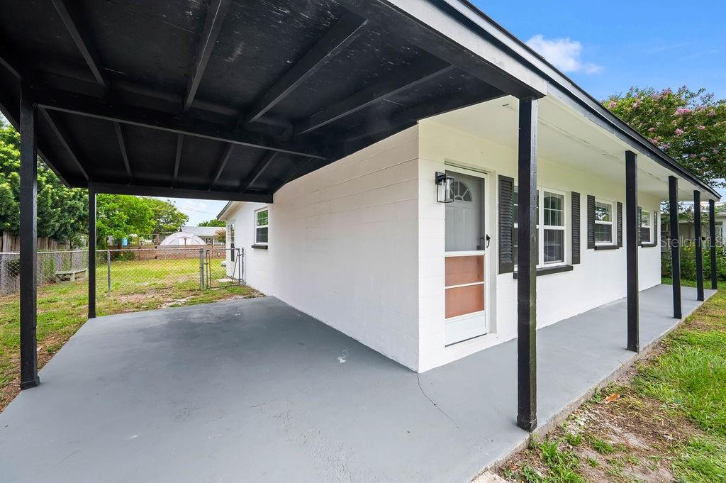 A white concrete block house features a covered carport and a front porch — 2204 SHELBY DRIVE, MELBOURNE, FL
