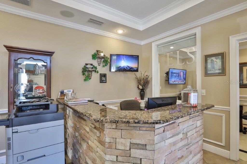 A reception area features a stone-front desk, granite countertop, and a printer in the foreground — 437 APOLLO BEACH BOULEVARD UNIT F-4, APOLLO BEACH, FL