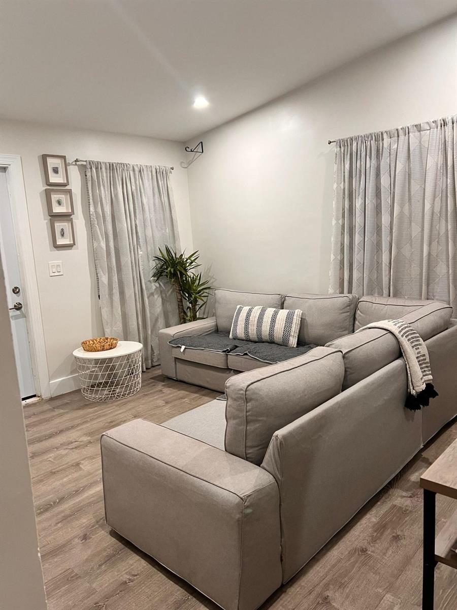 A living room features a gray sectional sofa, a white wire side table, and curtains — 555 NW 15th Court, Pompano Beach FL 33060, POMPANO BEACH, FL