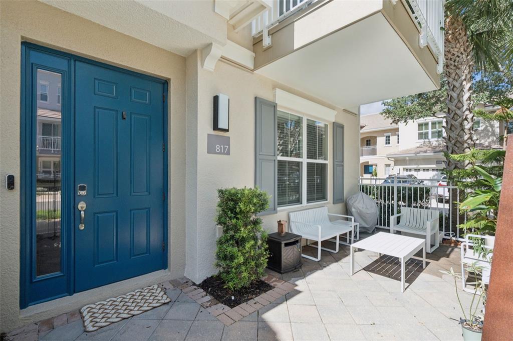 A blue front door opens onto a paved patio with white outdoor furniture and shutters — 817 GREYBULL RUN, LAKE MARY, FL