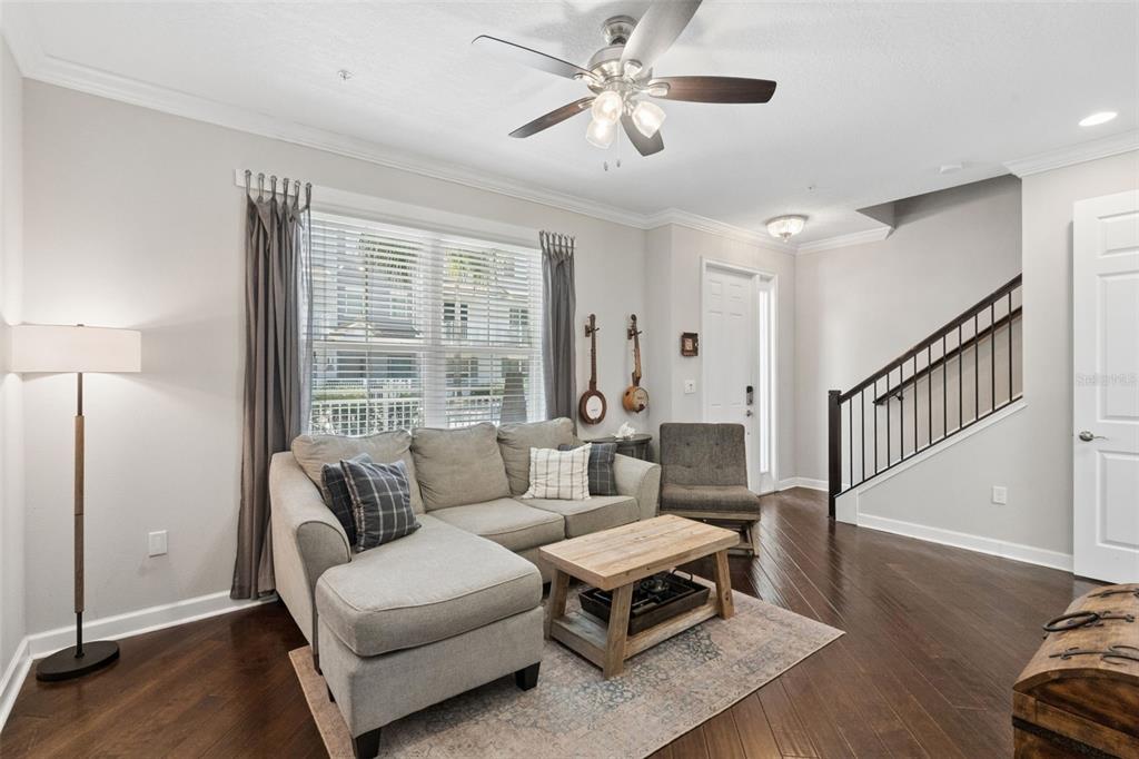 A living room features a gray sectional sofa, wooden coffee table, and dark hardwood floors — 817 GREYBULL RUN, LAKE MARY, FL
