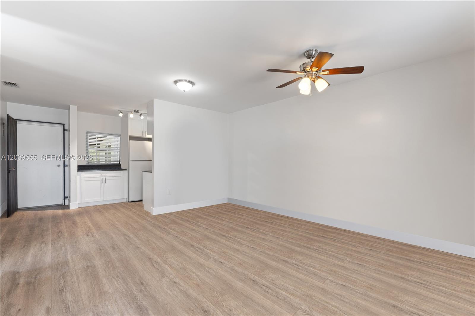 An open living area features light wood-look flooring, white walls, and a ceiling fan — 10544 SW 182nd St, Miami FL 33157, MIAMI, FL