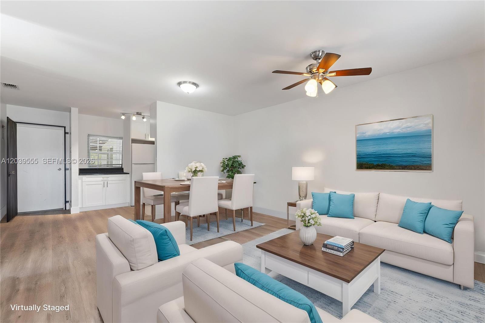 This virtually staged living and dining room features white furniture, blue accents, and wood flooring — 10544 SW 182nd St, Miami FL 33157, MIAMI, FL