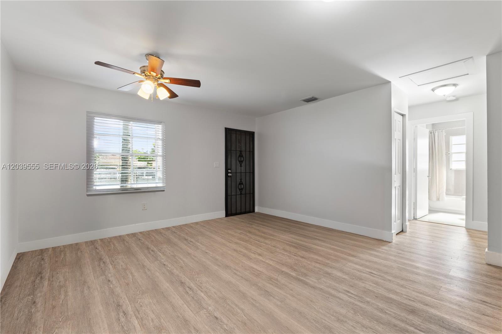 A room with light wood-look flooring, a ceiling fan, a window, and an adjacent bathroom — 10544 SW 182nd St, Miami FL 33157, MIAMI, FL