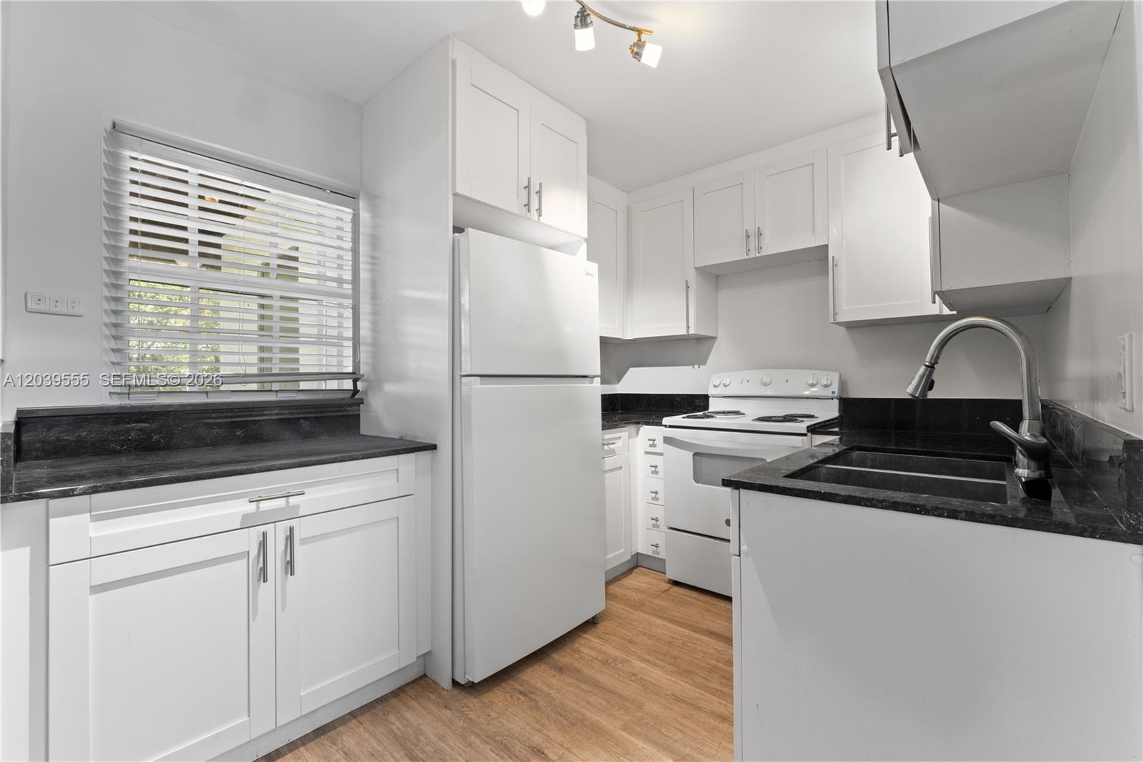 A kitchen features white cabinets, black countertops, a white refrigerator, and a white stove — 10544 SW 182nd St, Miami FL 33157, MIAMI, FL