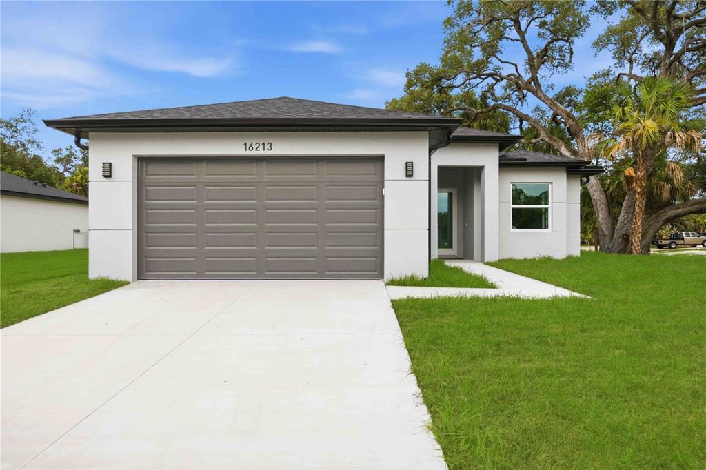 A modern, single-story house with a white exterior, gray garage door, and a concrete driveway — 16213 CASHMERE AVENUE, PORT CHARLOTTE, FL