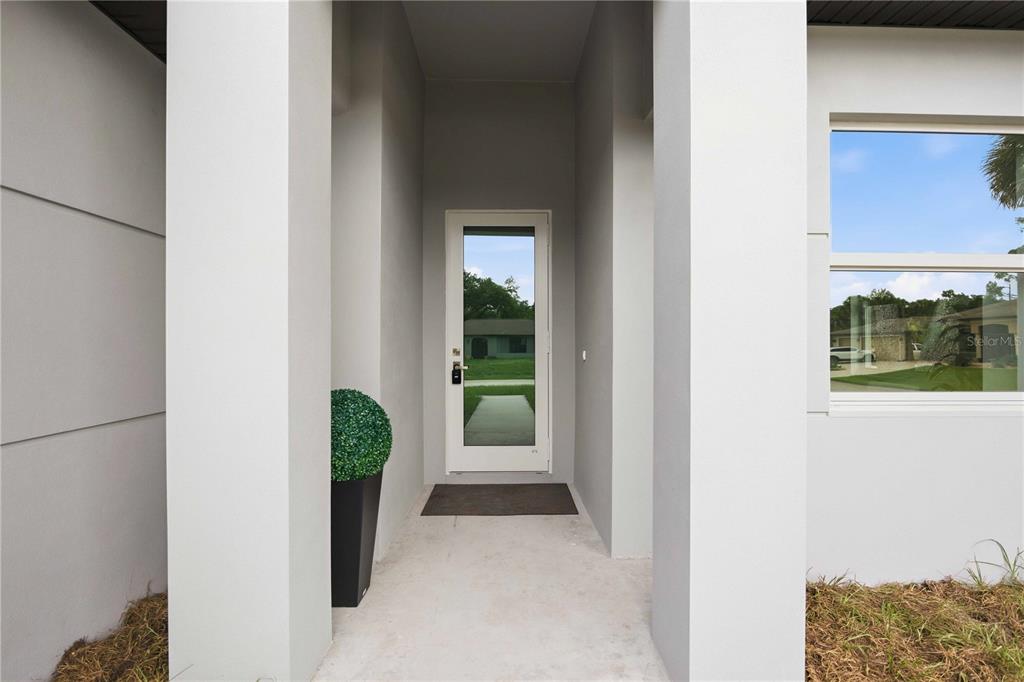 A modern home entrance features a white door with a glass panel between two columns — 16213 CASHMERE AVENUE, PORT CHARLOTTE, FL