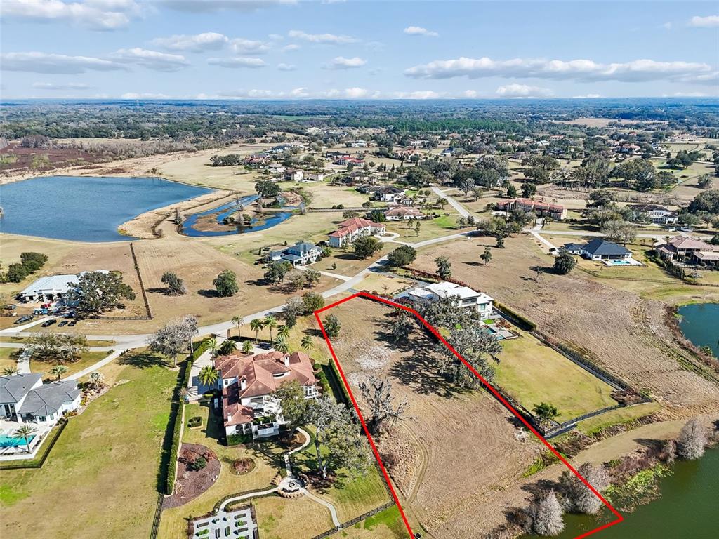 An aerial view shows a vacant rectangular lot outlined in red between two large houses — 10718 OSPREY LANDING WAY, THONOTOSASSA, FL